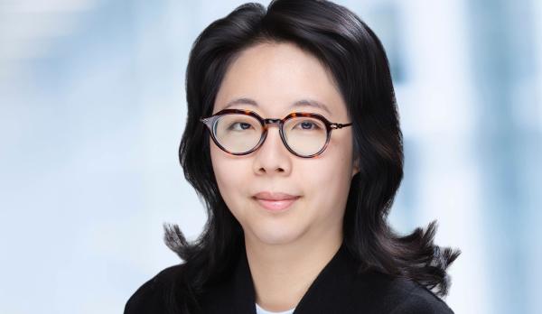 Photo of a woman with glasses and dark hear wearing a black sweater.