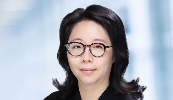 Photo of a woman with glasses and dark hear wearing a black sweater.