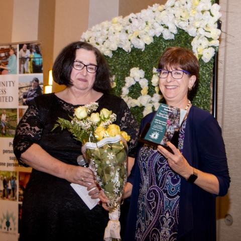 Photo of Elaine Katz holding her award and standing next to a woman. 