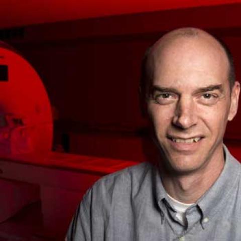 male scientist next to an MRA machine