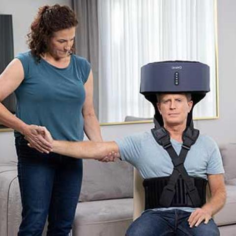 man with a mechanical device on his head with woman assisting him