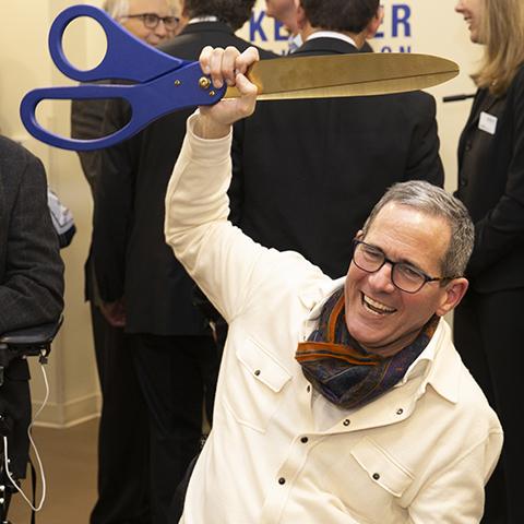 Tim Reynolds holding up big ceremonial scissors at Center for Spinal Stimulation ribbon cutting