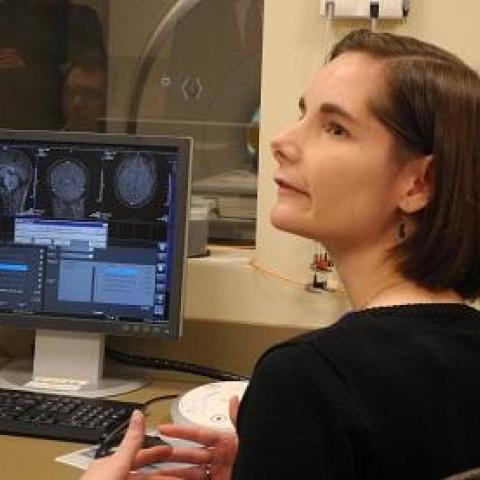 female scientist dr. weaver near a monitor showing diagram of a human brain