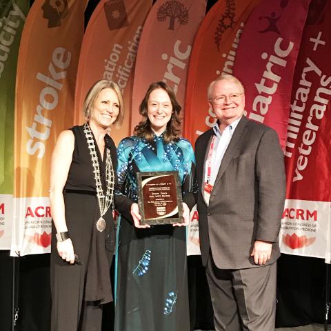 Dr. Jeanne Zanca receiving award at ACRM and standing with a male and female