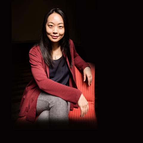 Dr. Peii Chen sitting on a chair against a black background 