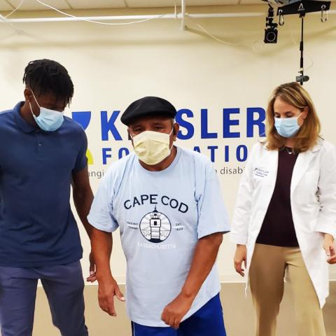 Three people wearing masks while walking in a lab to test equipment 