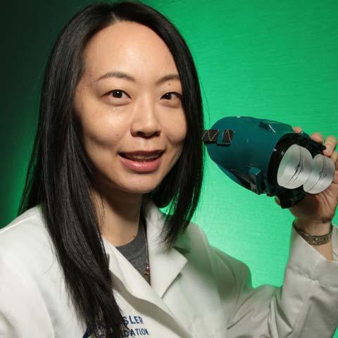 Dr. Chen holding a pair of prism goggles used in prism adaptation treatment