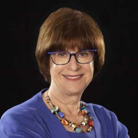 Lady with light brown hair wearing eyeglasses and a blue blouse.