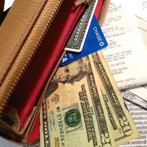 Wallet with credit cards, money and receipts scattered 