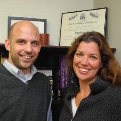 a male amd a female scientist smiling for the camera in their office