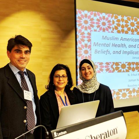 Three speakers standing in front of podium