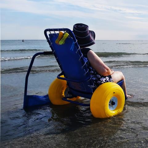 Image of a person in an accessible beach chair sitting in the water.