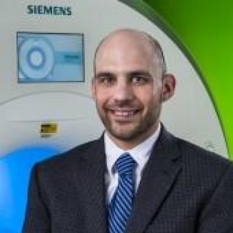 scientist smiling in front of the mri scanner