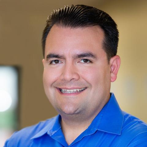 Image of Dr. Kirk Lercher. He is smiling and wearing a royal blue button up shirt.
