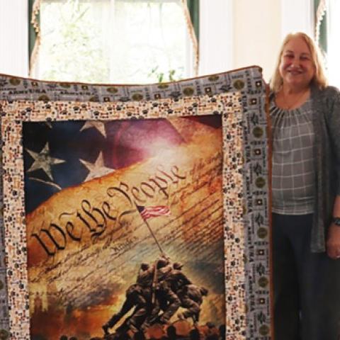 Woman wit a quilt that has the design of We The People Constitution