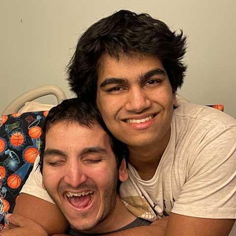 Two brothers smiling and hugging one another