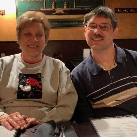 A woman and a man sitting side by side and smiling.