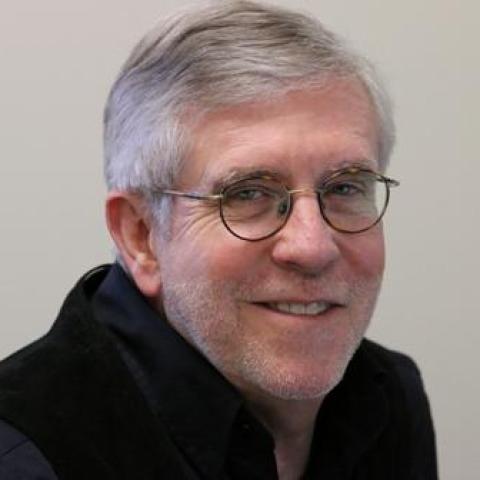 Dr. John Oneill wearing a black sweater and eyeglasses