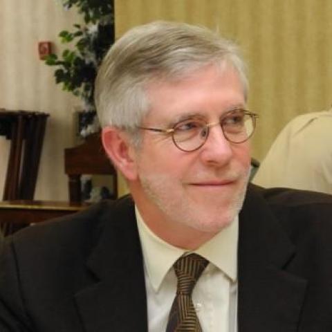 Dr. john oneill wearing a black suite and brown tie. 