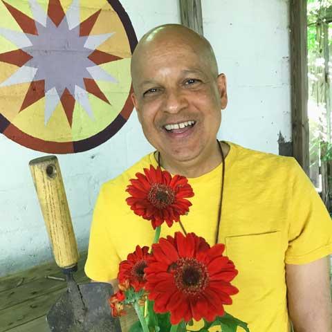 man with yellow t-shirt holding red flowers