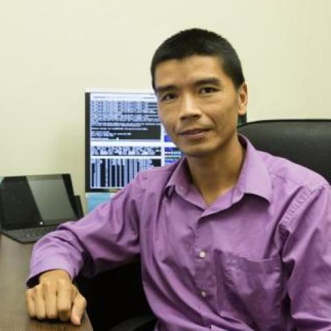 Dr jang wearing a purple shirt in front of a desktop computer