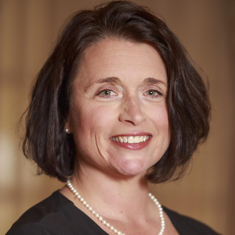 Light skin woman with dark brown hair wearing black blouse and pearls