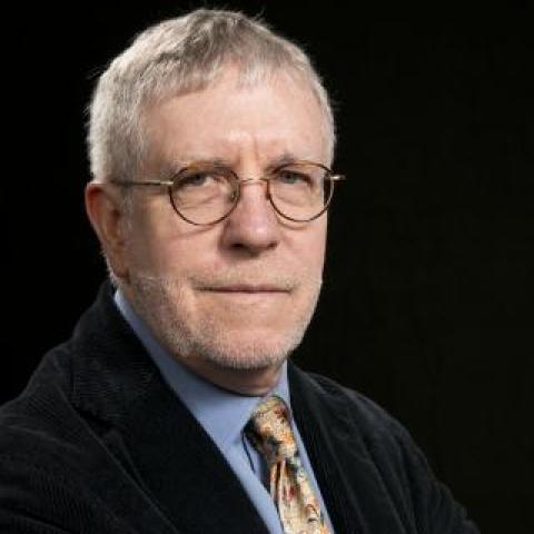 dr oneill with arms crossed, wearing a suit with a colorful tie