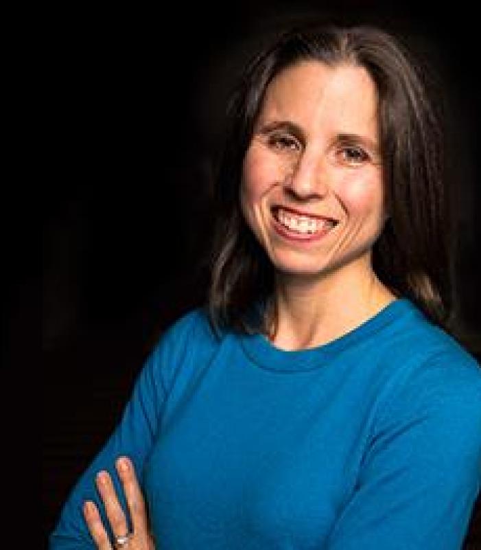 Director wearing blue blouse smiling for the camera