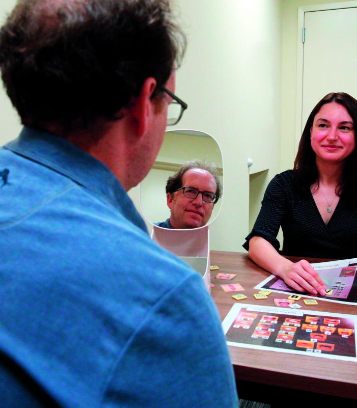 At Kessler Foundation, a researcher guides a participant through a structured task using letter tiles, a printed board, and a tabletop mirror for visual cueing. The scene illustrates evidence‑based methods that advance Kessler Foundation’s research in cognitive rehabilitation and stroke recovery, highlighting the organization’s commitment to translating clinical assessments into real‑world functional improvements. 