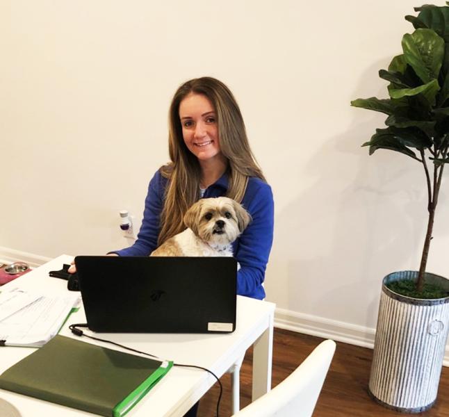 Kristen Costanza sitting with her dog next to a computer 
