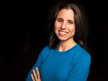 Director wearing blue blouse smiling for the camera