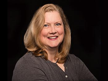 Director wearing a black blouse smiling for the camera