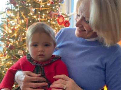 Pastora Goldner holding a baby in front of a christmas tree