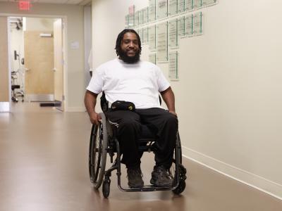 Man using a wheelchair sits in a long hallway