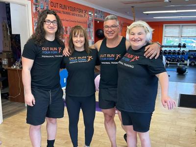 Family of four smile together for a photo in a fitness environment
