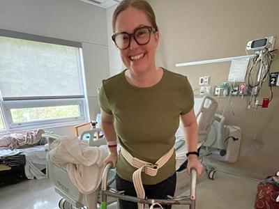 Female TBI participant standing with walker in hospital room